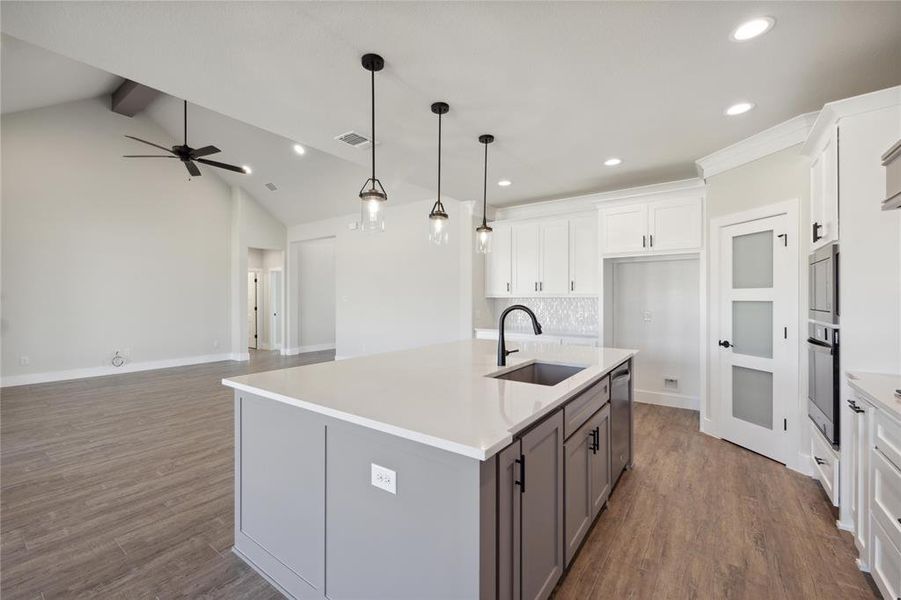 Kitchen with ceiling fan, white cabinets, an island with sink, appliances with stainless steel finishes, and lofted ceiling with beams