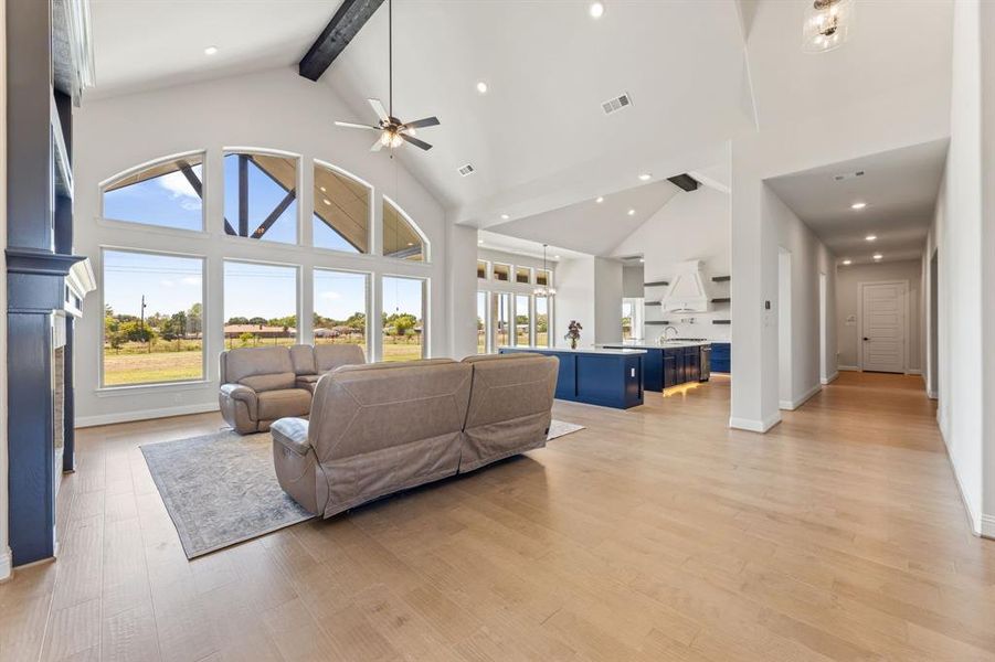 Living room with ceiling fan, beamed ceiling, sink, light hardwood / wood-style flooring, and high vaulted ceiling