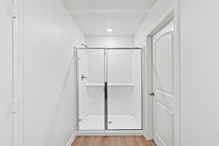 Bathroom featuring a shower with door and wood-style floors