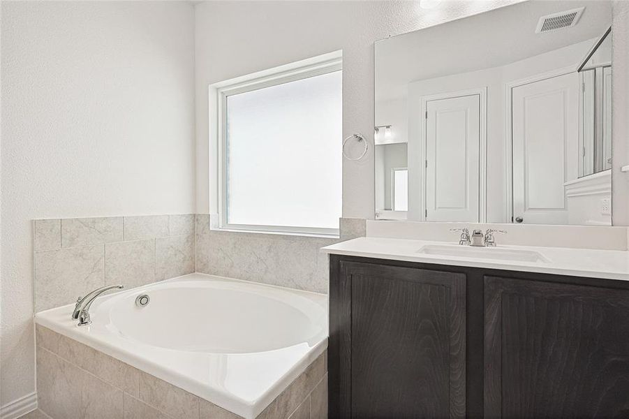 Bathroom with vanity and tiled bath