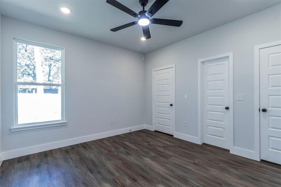 Unfurnished bedroom with multiple closets, ceiling fan, and dark hardwood / wood-style floors