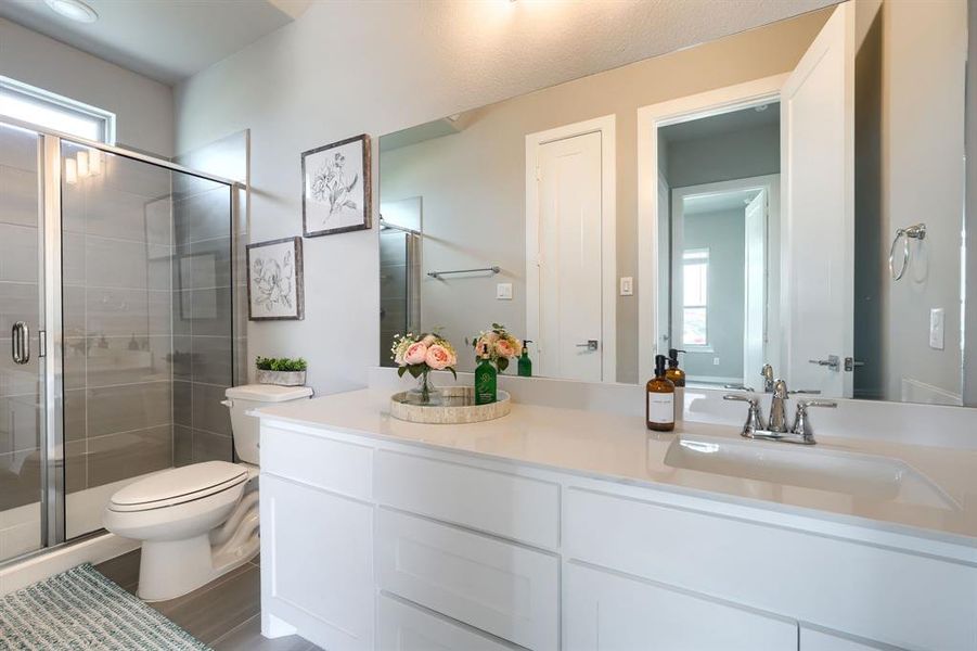 Bathroom with a wealth of natural light, vanity with extensive cabinet space, an enclosed shower, and toilet