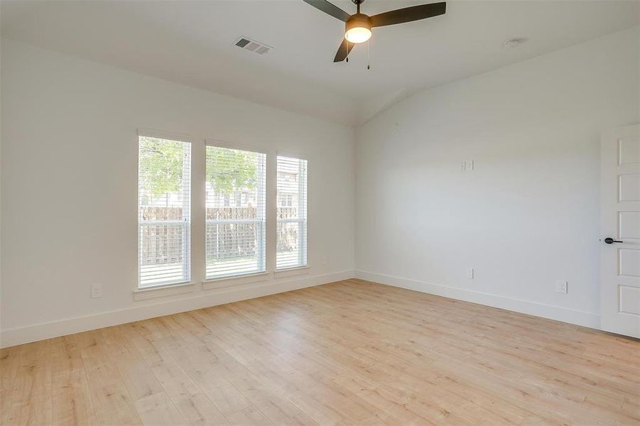 Empty room featuring vaulted ceiling, ceiling fan, and light hardwood / wood-style flooring