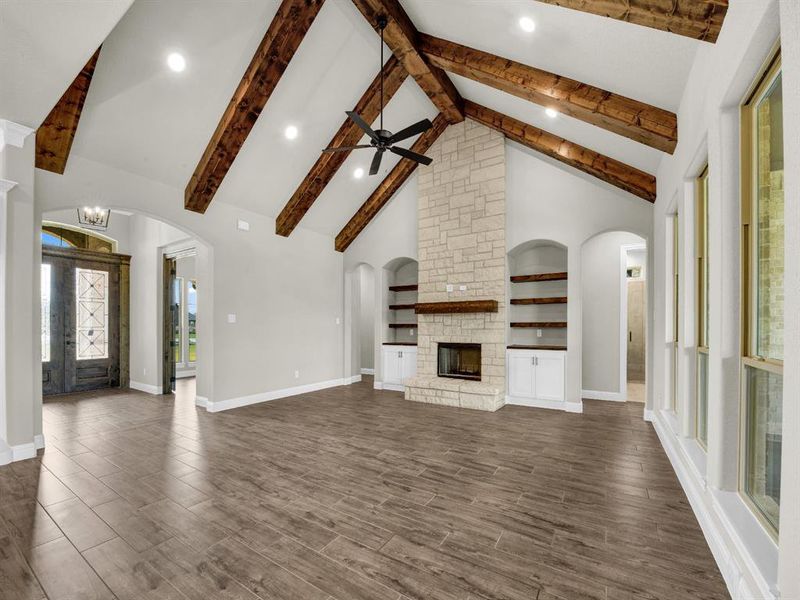 Unfurnished living room featuring ceiling fan with notable chandelier, a fireplace, dark hardwood / wood-style flooring, and beam ceiling