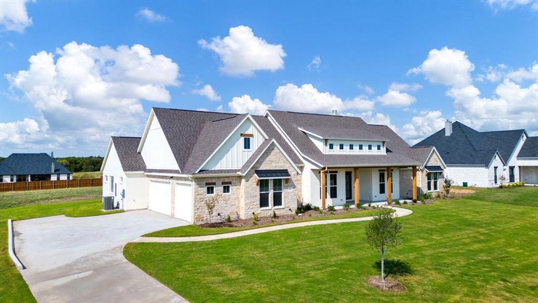 View of front of house featuring cooling unit, a garage, and a front lawn