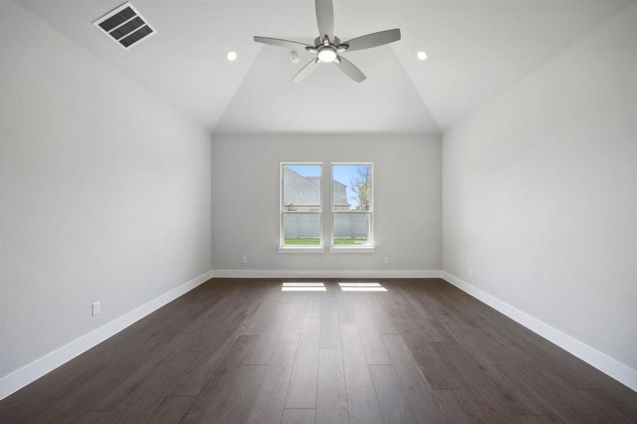 Empty room with dark hardwood / wood-style floors, vaulted ceiling, and ceiling fan