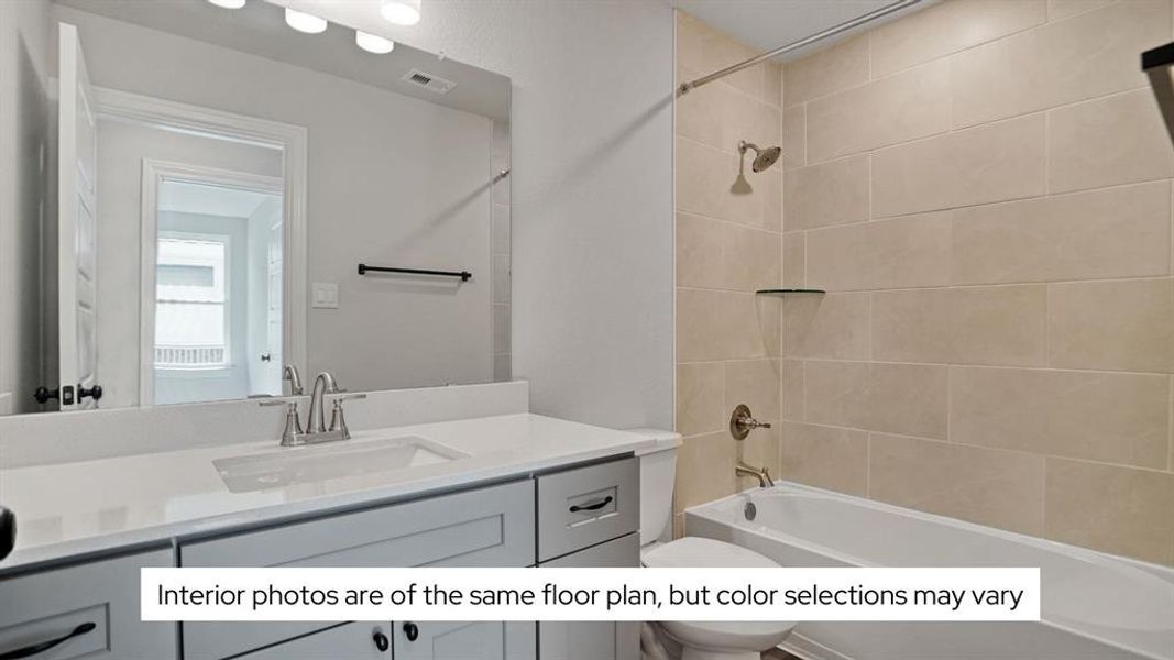 The secondary bath features a large vanity area and a tub/shower combo that is tiled to the ceiling.
