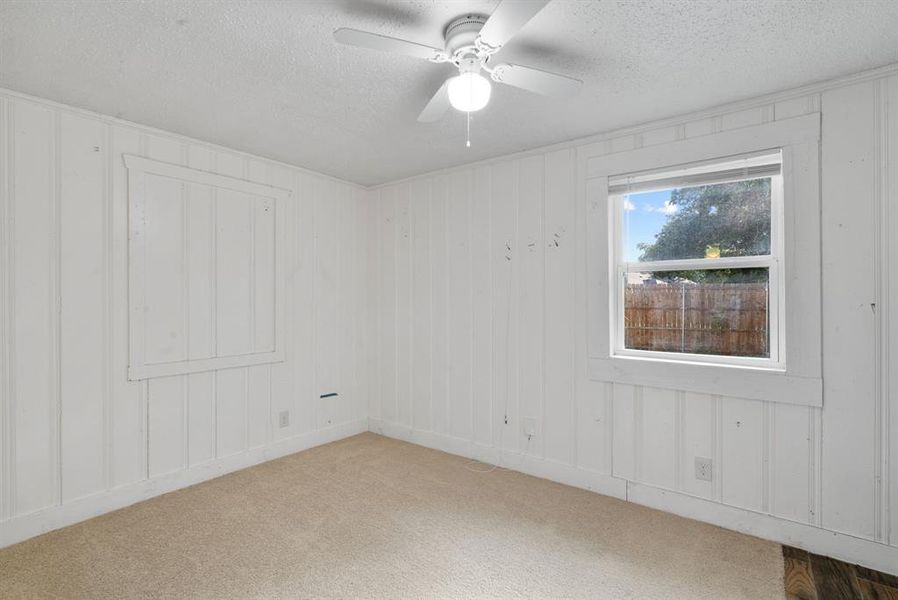 Empty room with ceiling fan, a textured ceiling, and carpet