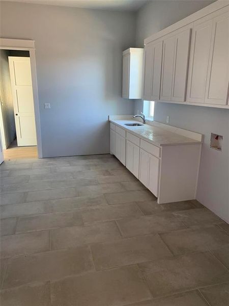 Kitchen featuring white cabinetry and sink