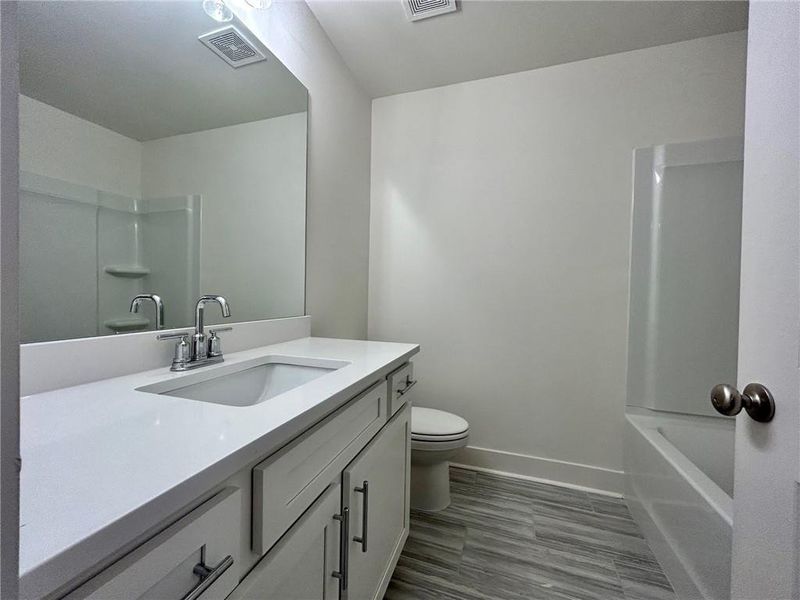Full bathroom with toilet, washtub / shower combination, vanity with extensive cabinet space, and tile flooring