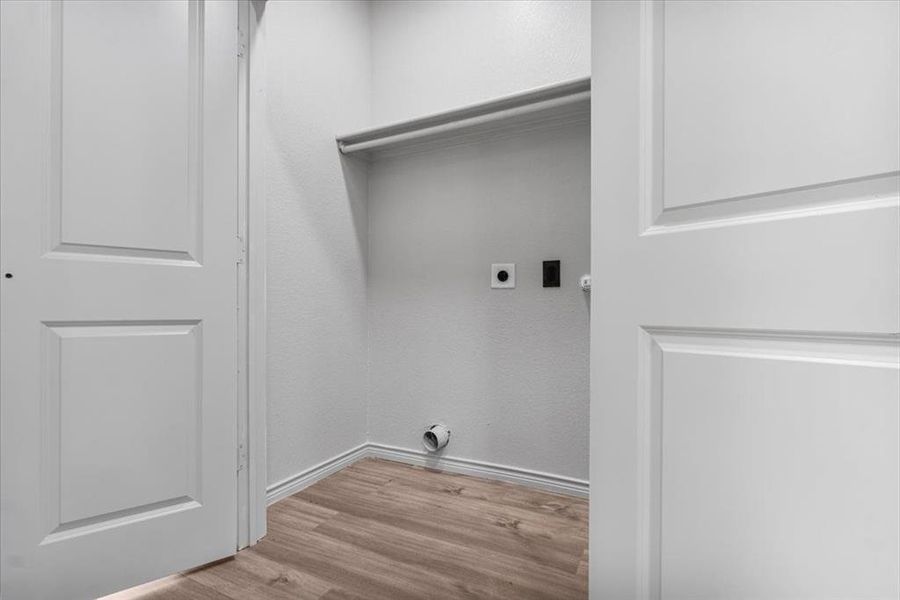 Washroom with light hardwood / wood-style floors and electric dryer hookup