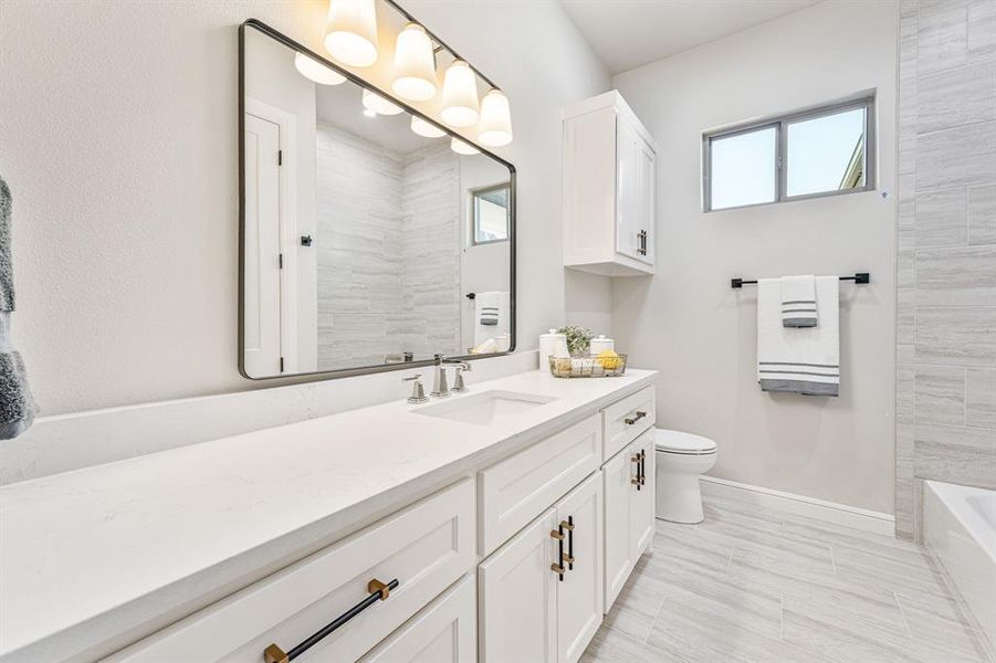 Full bathroom featuring vanity, tiled shower / bath, tile patterned flooring, and toilet