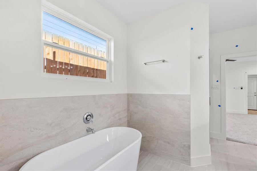 Bathroom featuring tile patterned floors, tile walls, and a washtub