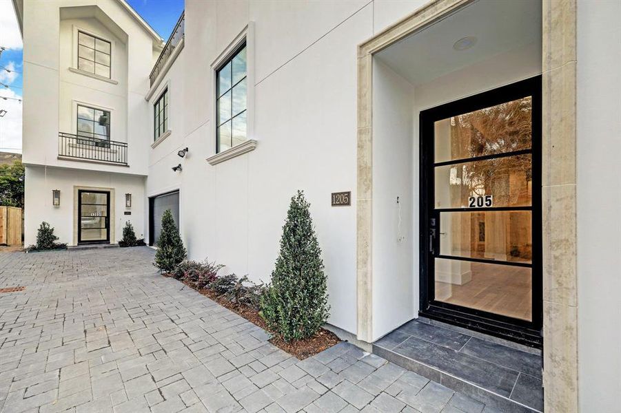 Beautiful contemporary glass entry door with stone surround welcomes you into the home.