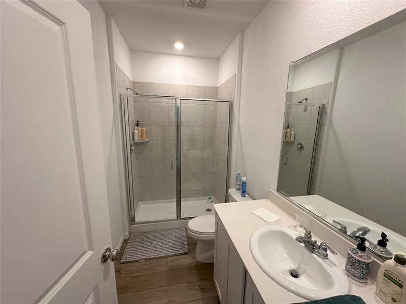 Bathroom with vanity, toilet, hardwood / wood-style flooring, and a shower with door