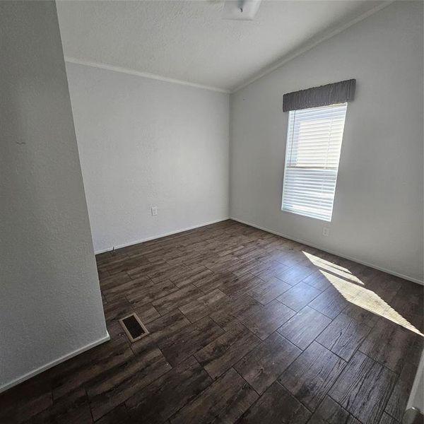 Spare room with vaulted ceiling, dark hardwood / wood-style floors, and ornamental molding