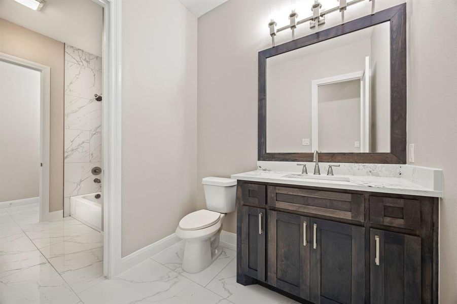 Full bathroom with vanity, tile patterned flooring, tiled shower / bath combo, and toilet