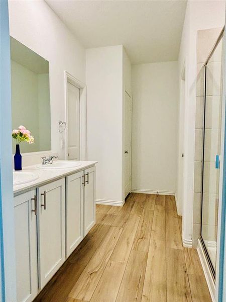 Bathroom with vanity, an enclosed shower, and wood-type flooring