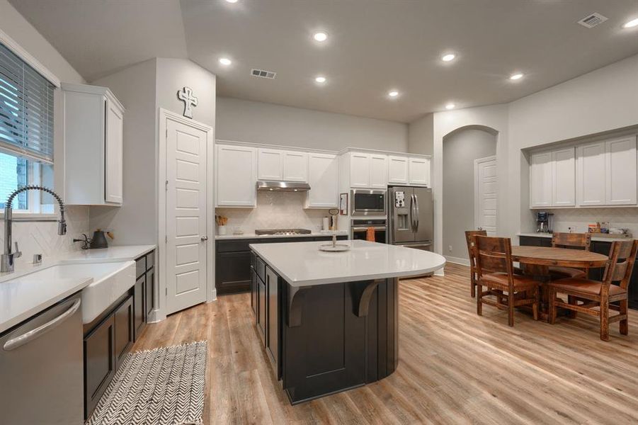 Kitchen featuring white cabinetry, light hardwood / wood-style floors, appliances with stainless steel finishes, and a kitchen island