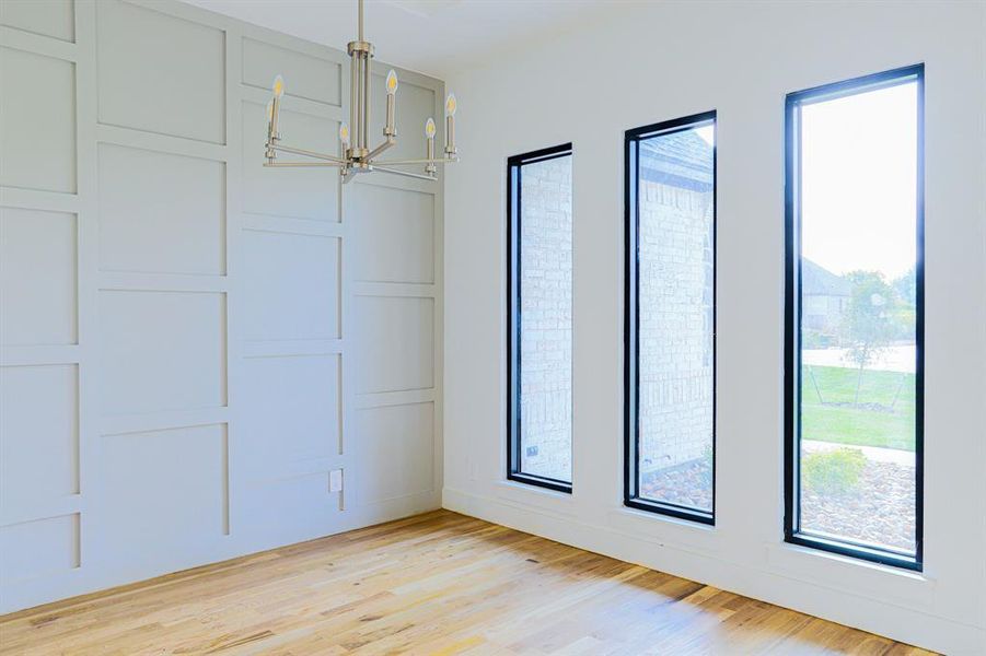 Empty room with an inviting chandelier and light hardwood / wood-style flooring