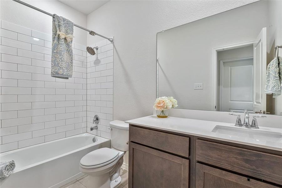 Full bathroom with tile floors, tiled shower / bath combo, toilet, and vanity with extensive cabinet space