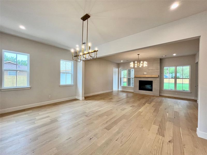 Unfurnished living room with plenty of natural light, a chandelier, and light hardwood / wood-style flooring