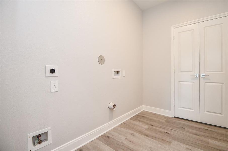 This is a modern utility room corner with neutral walls and wood-look flooring, featuring several outlets and hookups for utilities and electronics, as well as a large pantry.