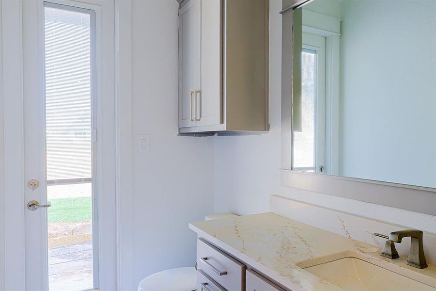 Bathroom with toilet, a wealth of natural light, and vanity