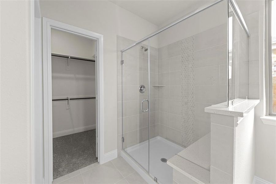 Bathroom with tile flooring and a shower with door