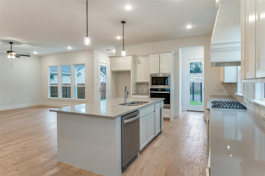 Kitchen featuring decorative backsplash, appliances with stainless steel finishes, sink, white cabinetry, and light hardwood / wood-style flooring