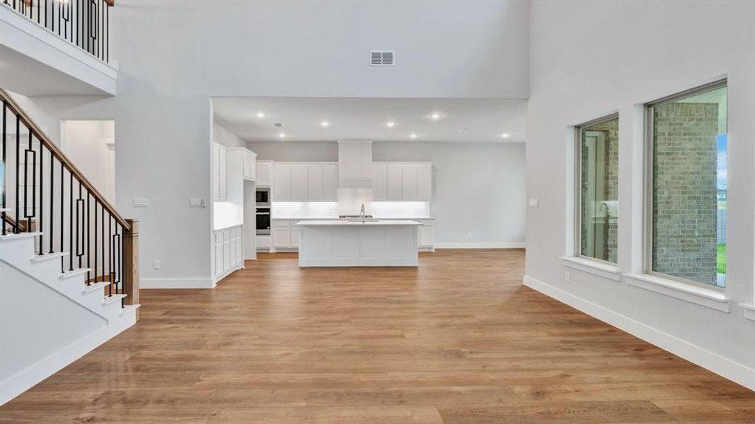 Unfurnished living room featuring light hardwood / wood-style floors, sink, and a high ceiling