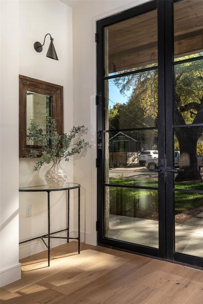 The front entryway features an art vignette with a sconce just inside the custom steel entry door.