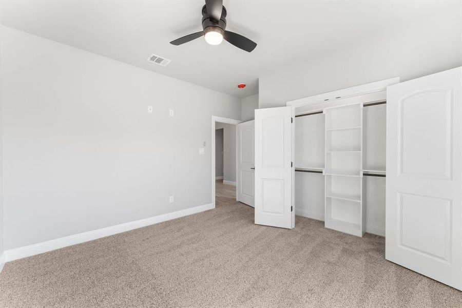 Unfurnished bedroom featuring ceiling fan, light colored carpet, and a closet