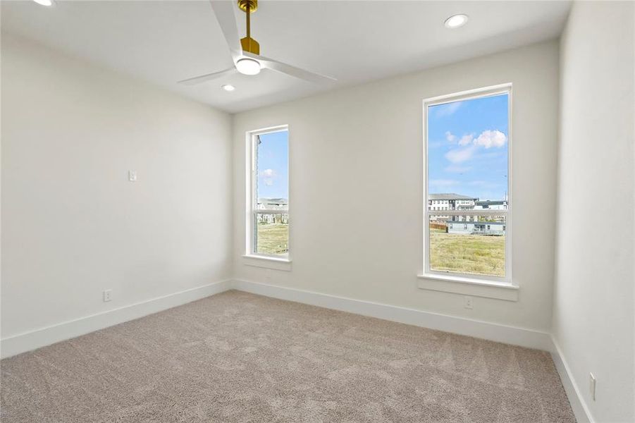 Unfurnished room featuring a wealth of natural light, light carpet, and ceiling fan