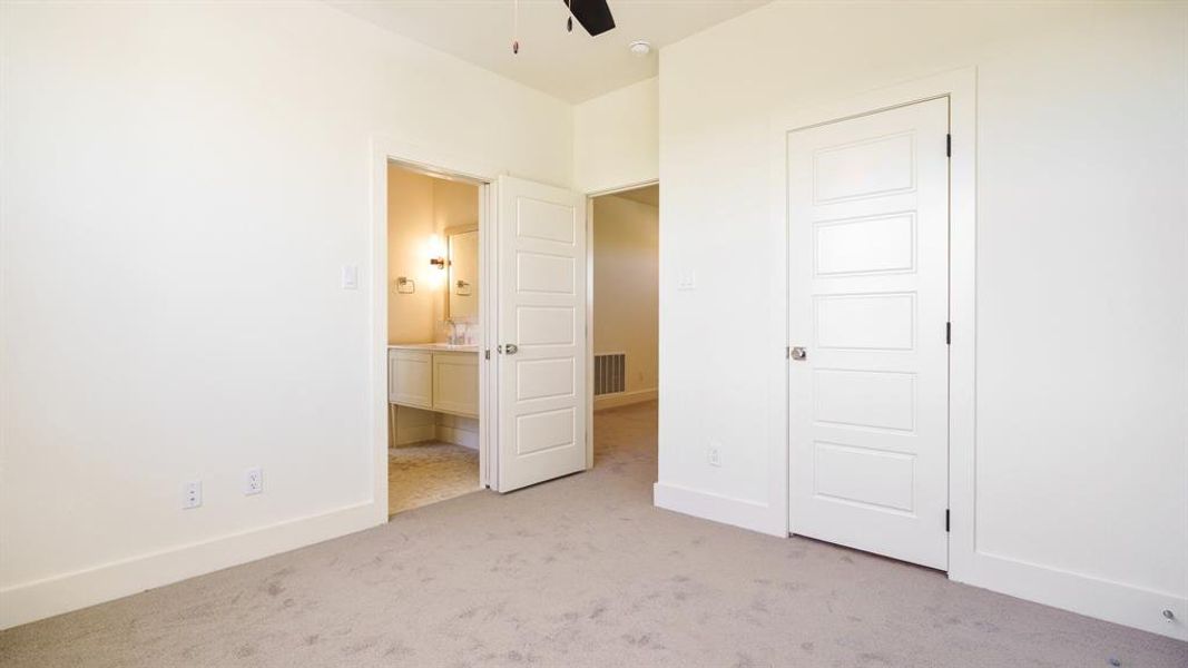 Unfurnished bedroom with ensuite bath, light colored carpet, and ceiling fan