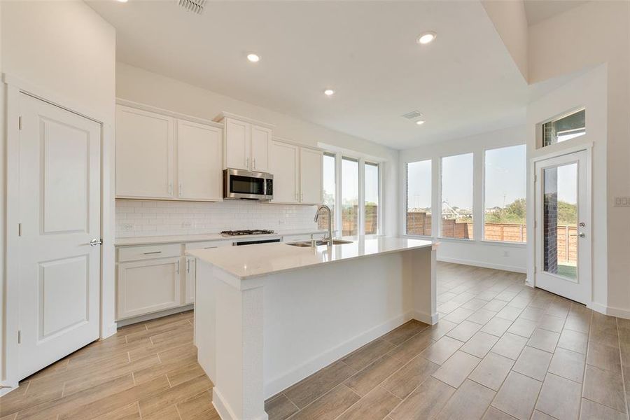 Kitchen featuring a wealth of natural light, sink, an island with sink, and white cabinets