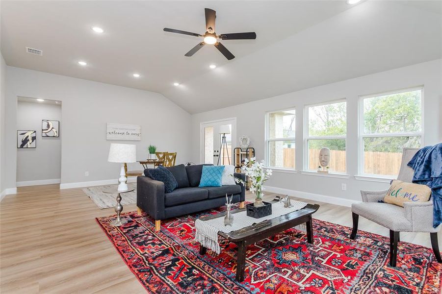 Living room featuring ceiling fan, lofted ceiling, and light wood-type flooring