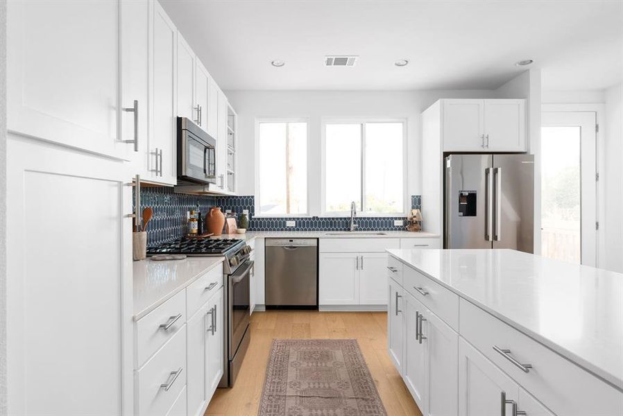 Spacious kitchen featuring pristine white cabinetry and modern appliances.