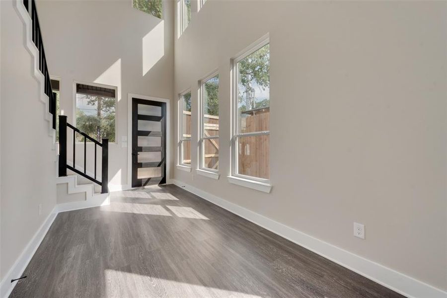 Entrance foyer featuring a wealth of natural light, a towering ceiling, and hardwood / wood-style flooring