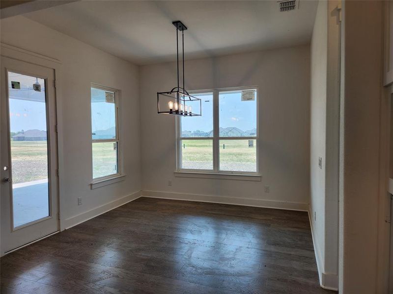 Unfurnished dining area with dark wood-type flooring and an inviting chandelier