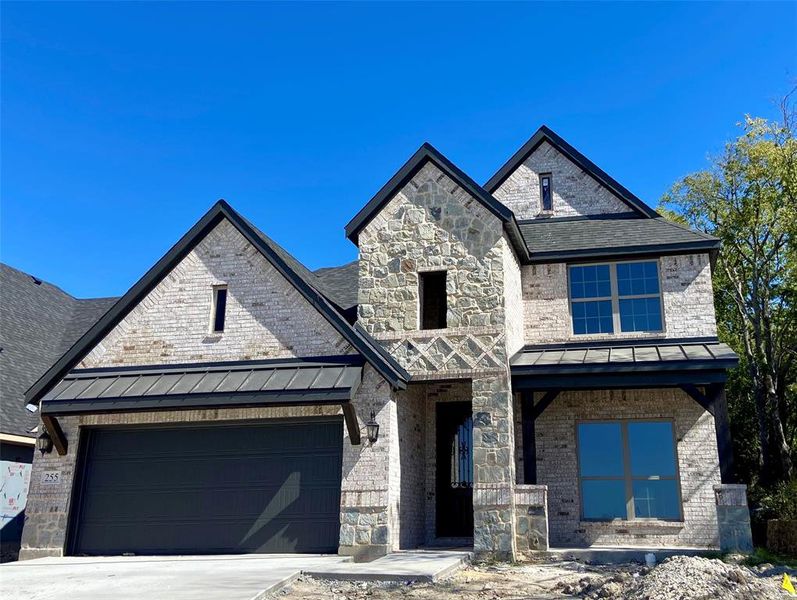 Gorgeous brick & stone 2 story home with metal roof on covered patio! Trees at rear and side.