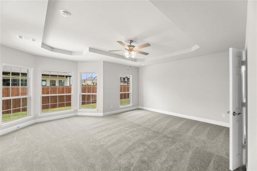 Unfurnished room with ceiling fan, a raised ceiling, and carpet floors