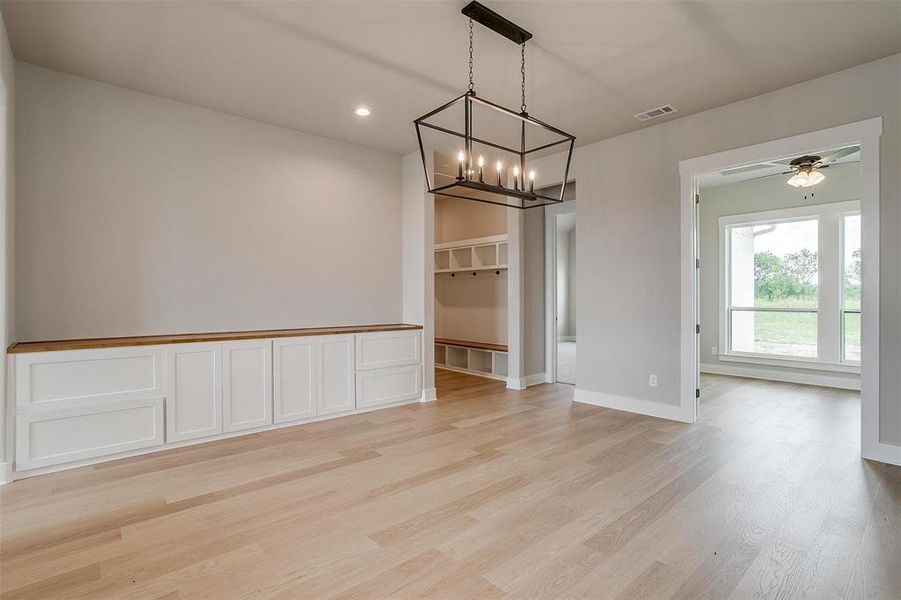 Unfurnished dining area featuring light hardwood / wood-style flooring and ceiling fan with notable chandelier