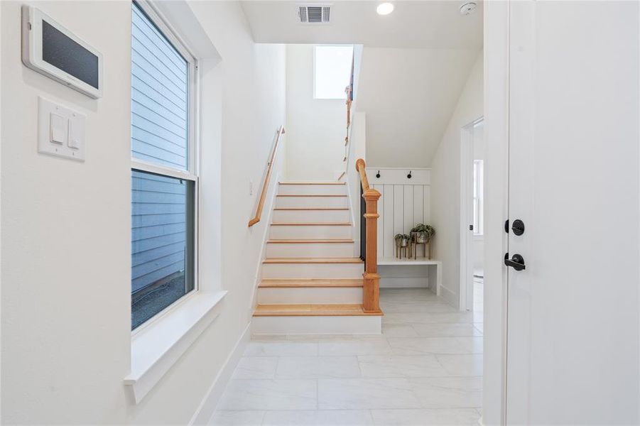 The stunning entryway captivates with its intricate tile flooring, while a practical mud section provides a designated space for outdoor wear, combining elegance and functionality in the home's first impression.