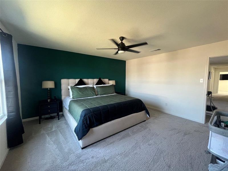 Carpeted bedroom featuring a textured ceiling and ceiling fan