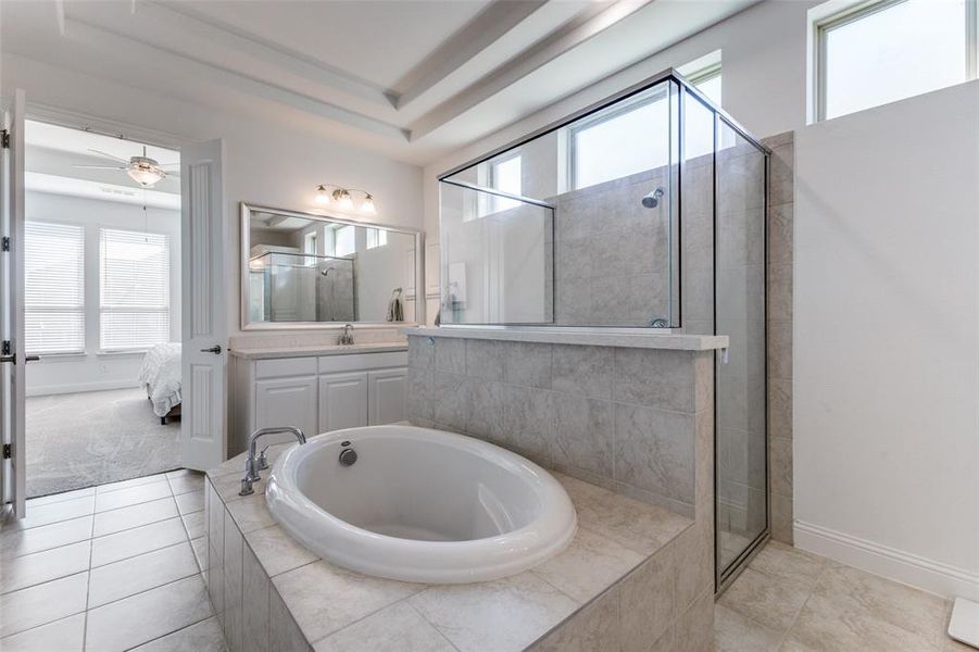 Bathroom featuring shower with separate bathtub, patterned tile flooring, plenty of natural light, and vanity