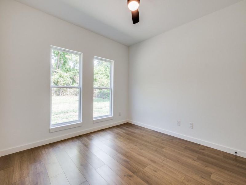 Empty room with ceiling fan and hardwood / wood-style flooring