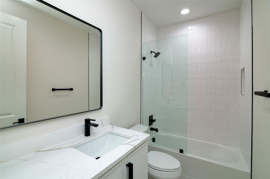 Full bathroom with tiled shower / bath combo, vanity, and toilet