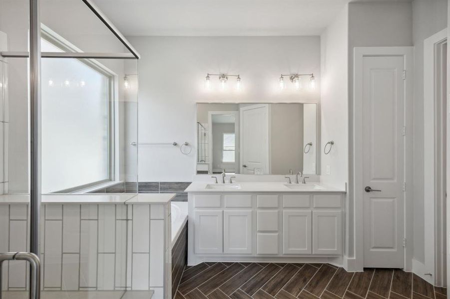 Bathroom featuring hardwood / wood-style flooring, a healthy amount of sunlight, double sink vanity, and a bathtub