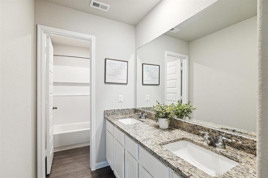 Upstairs secondary bathroom is well appointed with double sinks, lots of cabinet storage and vinyl plank flooring.